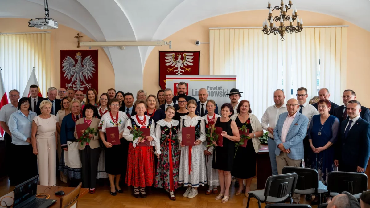 Grupa laureatów trzymających dyplomy i statuetki pozuje do wspólnego zdjęcia z władzami powiatu limanowskiego.