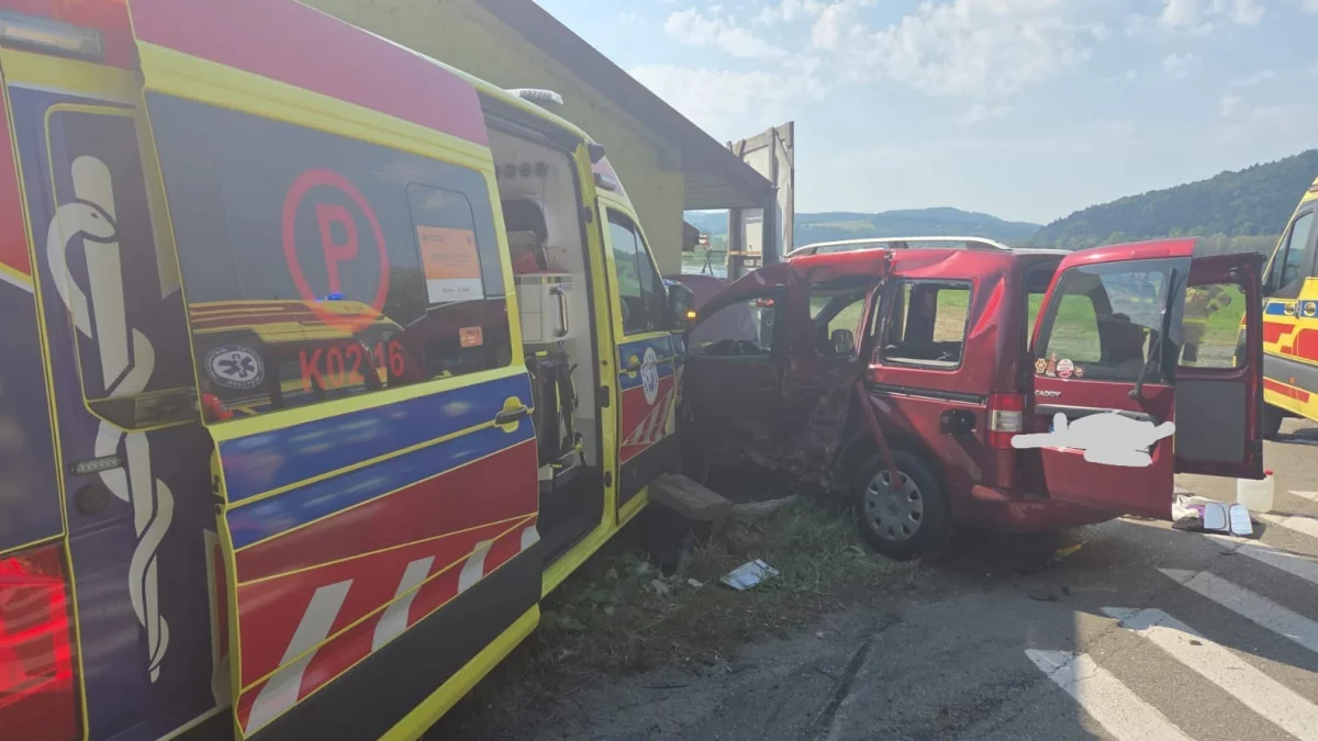 Zmiażdżony lewy bok czerwonego samochodu osobowego uderzonego przez ambulans.