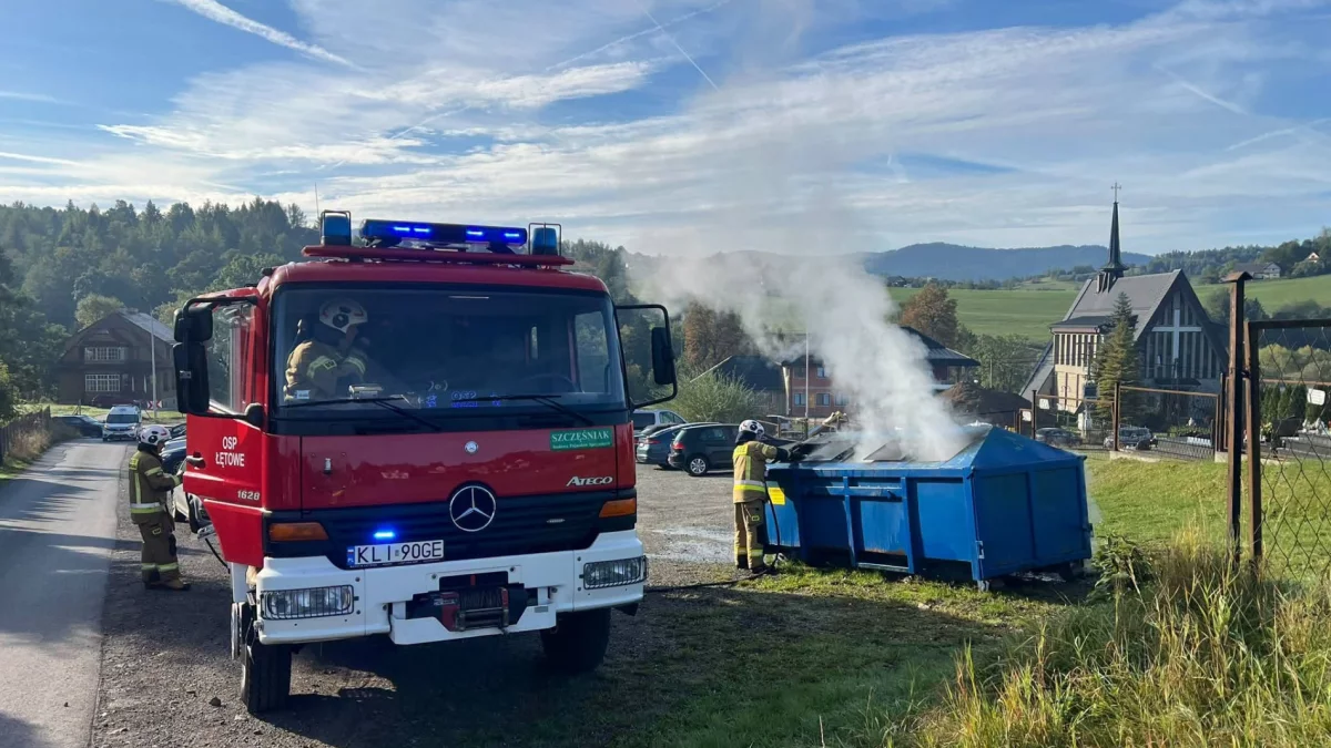 Strażacy gaszący pożar kontenera na śmieci w Łętowem
