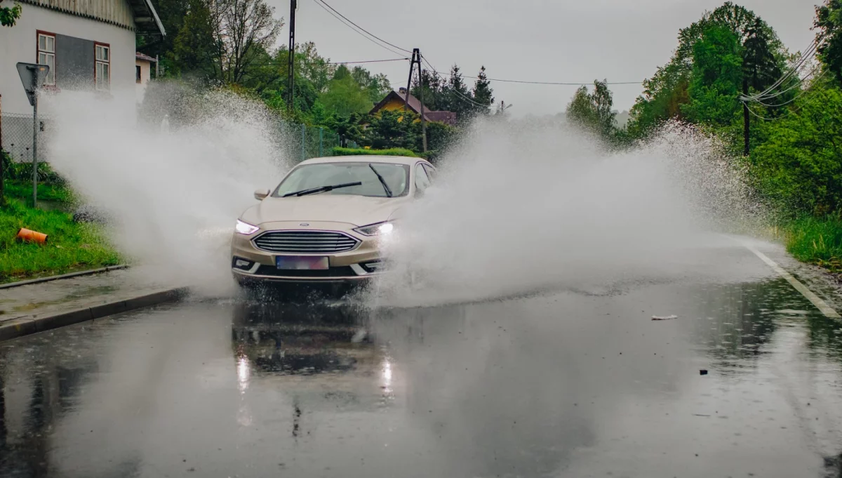 Samochód przejeżdżający przez stojącą na jezdni wodę