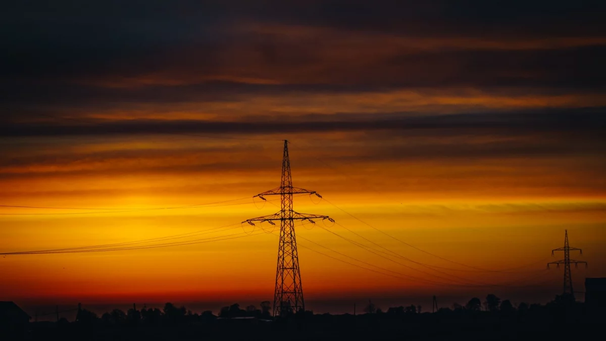 Słupy energetyczne i linie wysokiego napięcia na tle nieba w powiecie limanowskim.