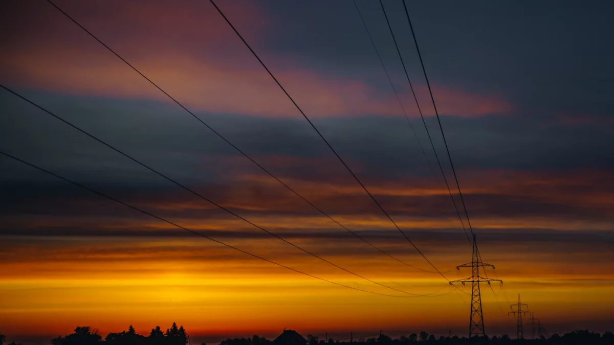 Słupy energetyczne i linie wysokiego napięcia na tle nieba w powiecie limanowskim.
