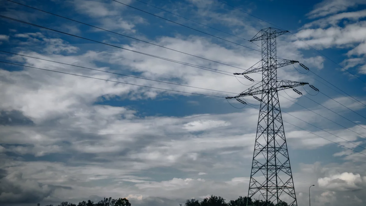 Słupy energetyczne i linie wysokiego napięcia na tle nieba w powiecie limanowskim.