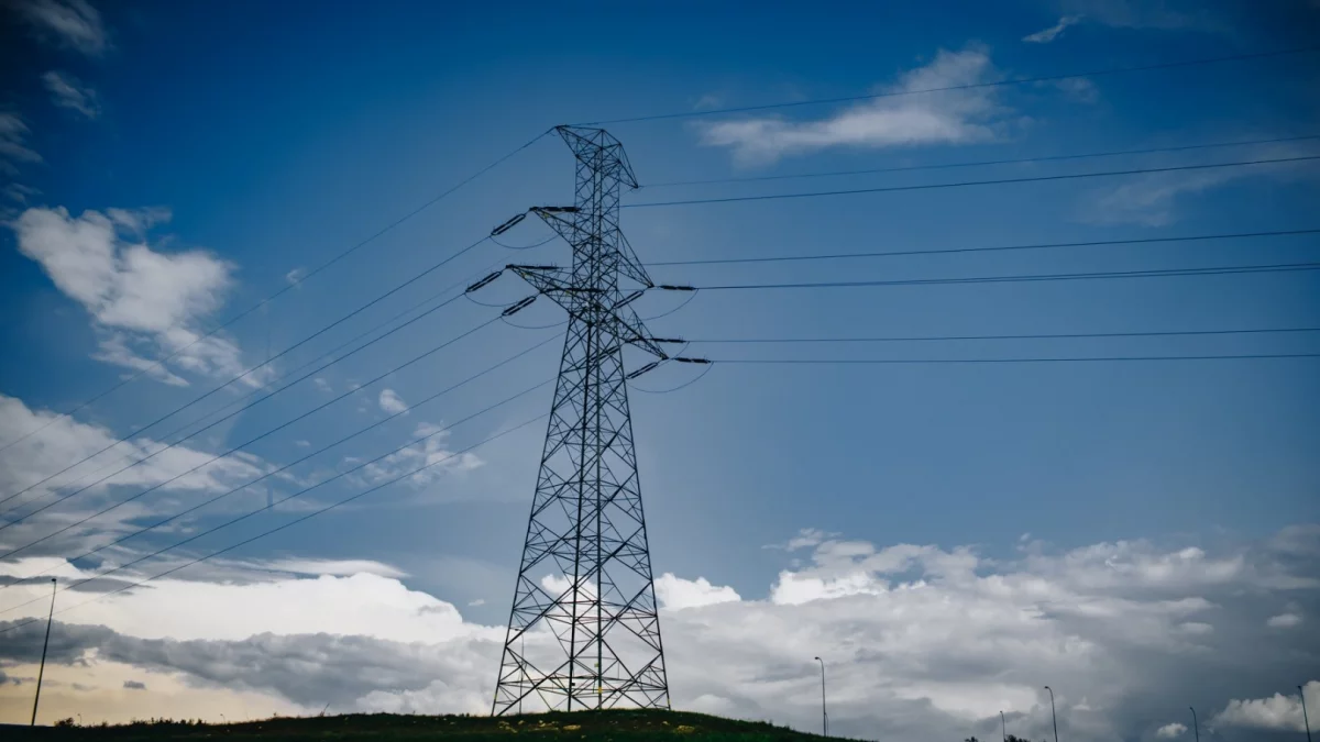 Słupy energetyczne i linie wysokiego napięcia na tle nieba w powiecie limanowskim.