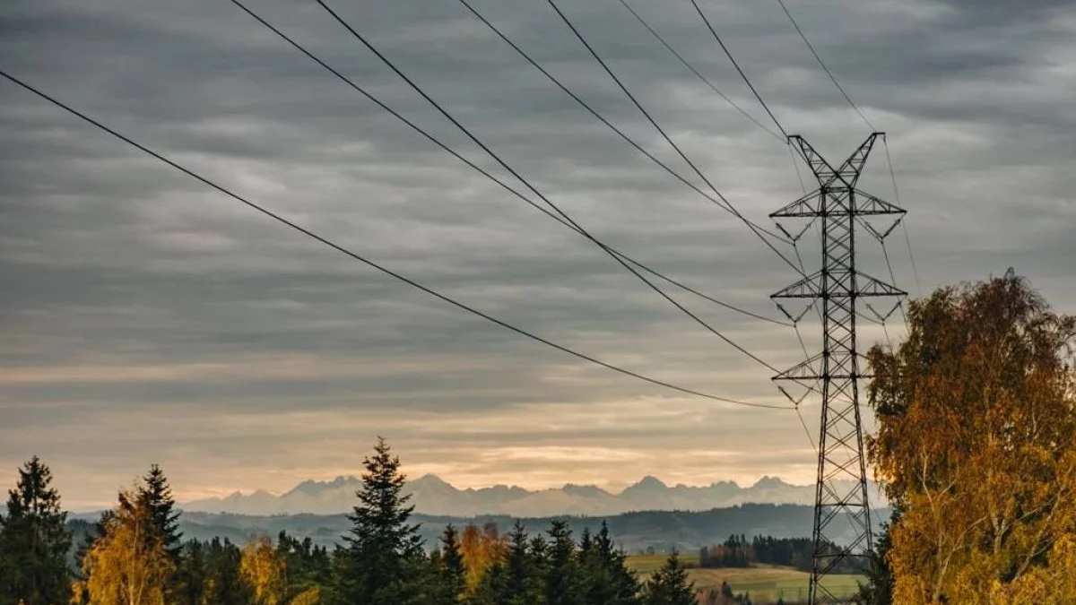 Słupy energetyczne i linie wysokiego napięcia na tle nieba w powiecie limanowskim.
