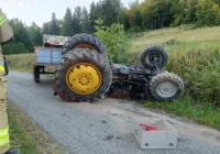 Ciągnik przewrócił się na stromym zjeździe, dwie osoby w szpitalu - zdjęcie główne