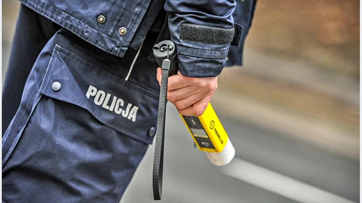 Policjant trzymający urządzenie do pomiaru zawartości alkoholu w wydychanym powietrzu