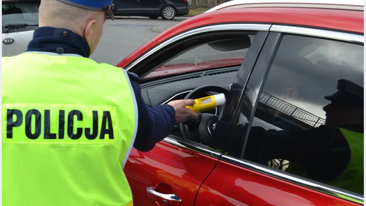 Policjant podczas badania trzeźwości kierowcy samochodu osobowego