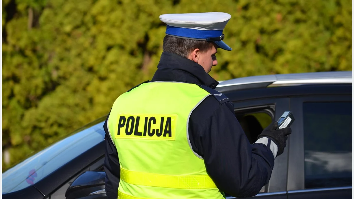 Policjant drogówki przeprowadzający badanie trzeźwości kierowcy podczas akcji Alkohol i narkotyki.