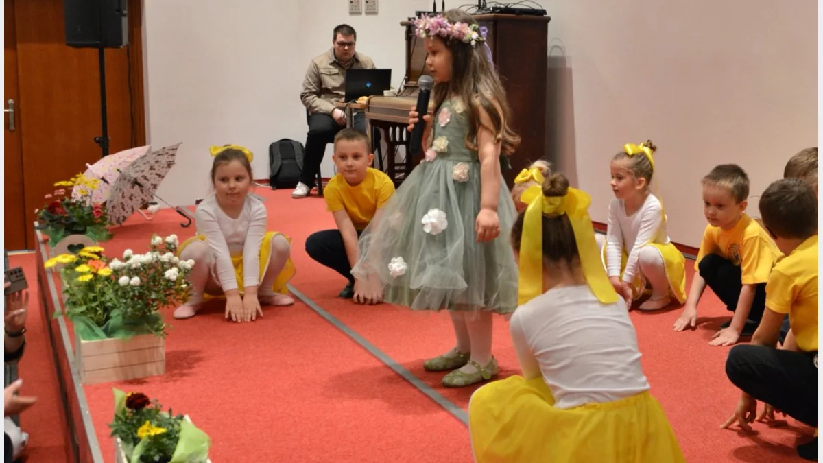 Dzieci w kolorowych strojach podczas występów wokalno-tanecznych na scenie w Bibliotece Publicznej w Tymbarku