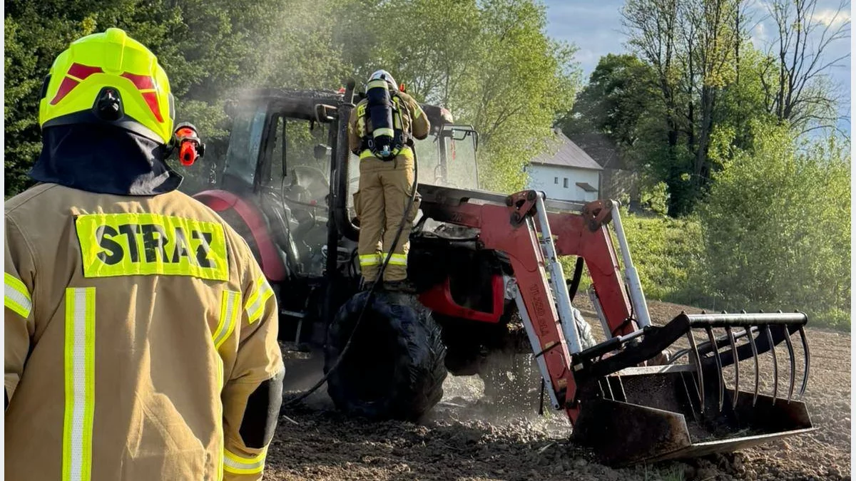 Strażacy gaszący pożar ciągnika rolniczego w Janowicach