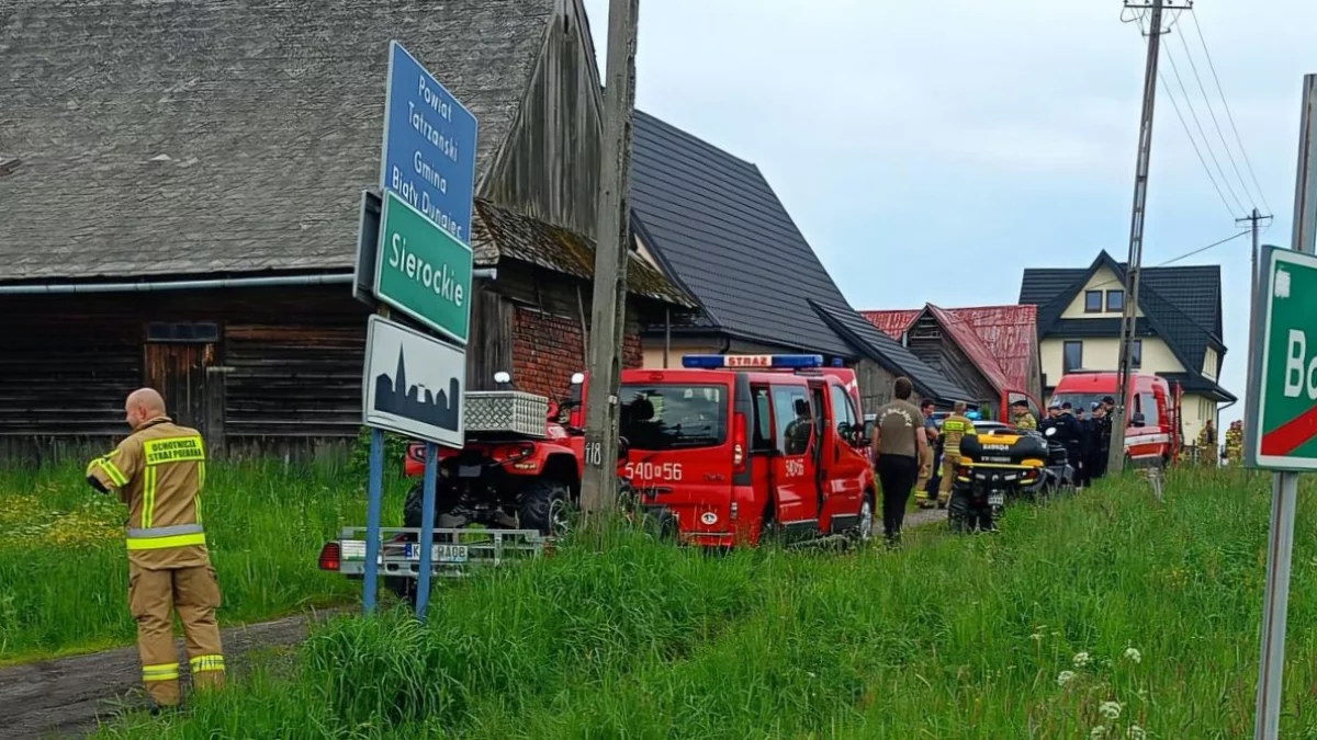 Radiowóz policyjny i wozy strażackie biorące udział w akcji poszukiwawczej 