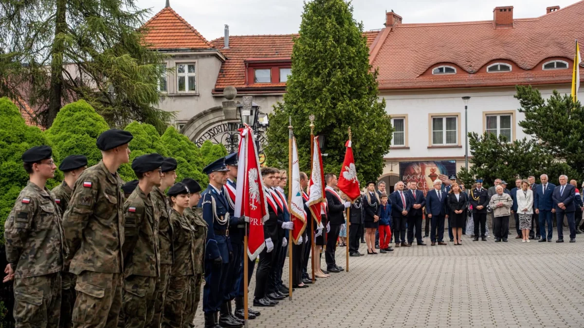 Oficjalne delegacje z wieńcami przed tablicami pamiątkowymi w podcieniach bazyliki w Limanowej